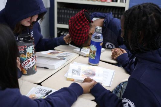 Students hold hands in prayer prior to their study of the Great Controversy.
