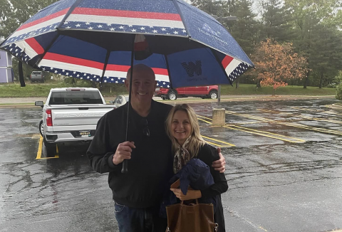Mike Kinzel met each car & offered protection with his umbrella from the rain. Here he escorts Marcia Somerville to the shelter of the portico.